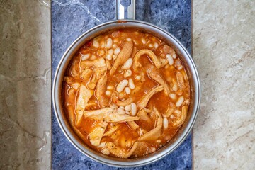 A classic Brazilian dish known as dobradinha, prepared with beef tripe, white beans, and tropical spices, served with traditional farofa made with toasted cassava flour.