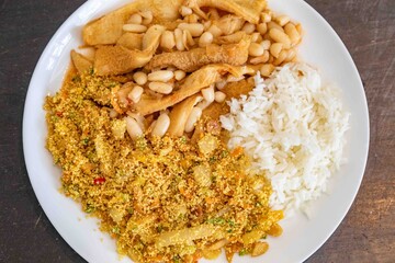 A classic Brazilian dish known as dobradinha, prepared with beef tripe, white beans, and tropical spices, served with traditional farofa made with toasted cassava flour.