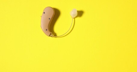 Hearing aid spinning on yellow background, top view