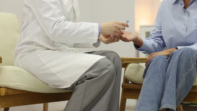 Diabetes. Doctor checking patient's blood sugar level with lancet pen and glucometer on armchair indoors, closeup. Camera moving forward