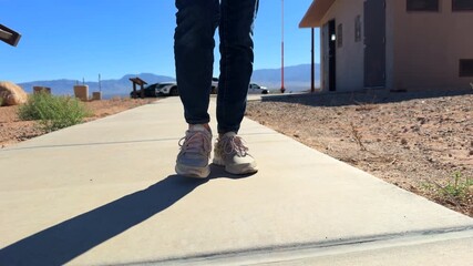Woman walking closeup slow motion front view on desert sidewalk