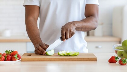 A person is slicing a green apple on a wooden cutting board.