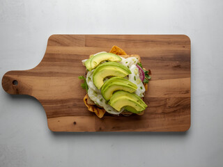 Avocado toast with neatly fanned slices on toasted bread placed on wooden table, top view in soft studio light, simple food styling for cafe menus.