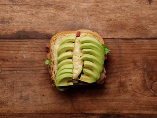 Avocado toast with neatly fanned slices on toasted bread placed on wooden table, top view in soft studio light, simple food styling for cafe menus.