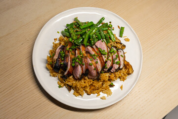 A plate of fried rice with duck and green beans.