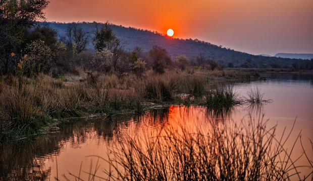 Fototapeta sunset over a body of water dam at Mokolodi Nature Reserve, located near Gaborone, Botswana