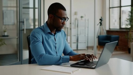 A focused man working on a laptop at his office desk Stock Video - Powered by Adobe