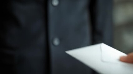 Person in dark suit offering a card