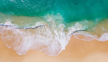 A breathtaking aerial top-down view of turquoise ocean waves gently lapping against a pristine golden sandy beach shore