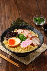 a Tonkotsu ramen bowl of traditional Japanese ramen with slices of chicken, halved boiled egg, seaweed, green onions, and other toppings