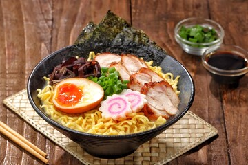 a Tonkotsu ramen bowl of traditional Japanese ramen with slices of chicken, halved boiled egg, seaweed, green onions, and other toppings