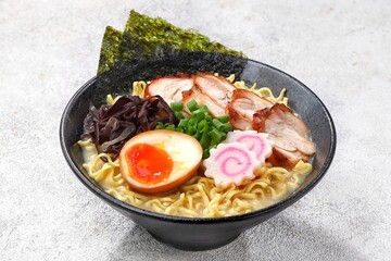 a Tonkotsu ramen bowl of traditional Japanese ramen with slices of chicken, halved boiled egg, seaweed, green onions, and other toppings