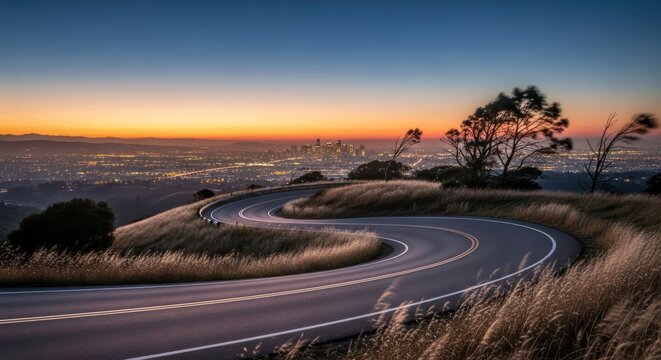 Serpentine road leading to illuminated cityscape under twilight horizon scenery