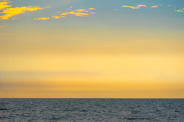 Nature sky breathtaking golden sunset over a calm ocean, with the entire sky and water bathed in brilliant shades of yellow and orange. Streaky clouds enhance the dramatic display of light	
