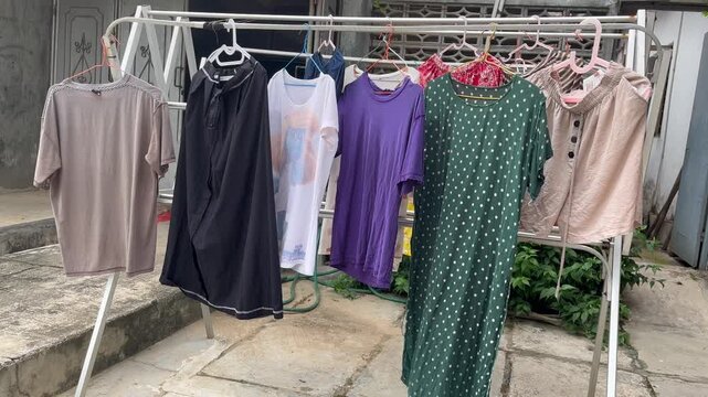 Clothes Drying on Rack Outdoors in Sunlight. Freshly washed clothes hanging on a drying rack outdoors under natural sunlight. Concept of eco-friendly laundry, air drying, and sustainable living.
