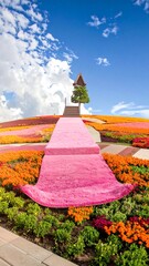 A vibrant garden path leads up a hillside of colorful flowers towards a small structure under a blue sky