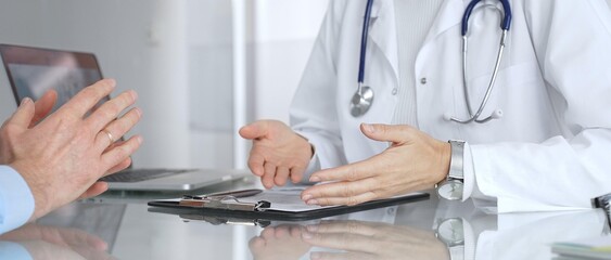 Doctor discussing medical information with patient during consultation, providing expert healthcare advice in clinic. Medicine, healthcare and science concept