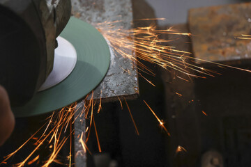 Close up of worker using an angle grinder to cut metal, creating bright sparks. industrial process shows focused and intense scene in workshop