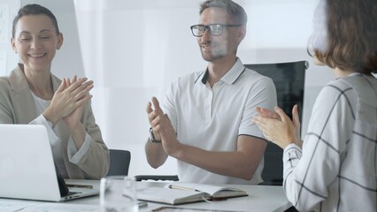 Professional team applauding, celebrating collaborative success and recognizing outstanding performance during corporate meeting in office. Business people concept