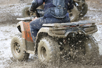 Exciting off road adventure with rider on an ATV kicking up mud and dirt. Extreme sport action showing thrill and power of quad bike riding in wet terrain © Core