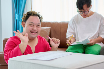 A man with down syndrome are engaging in an activity, displaying happiness and focus. One individual is smiling and waving, while the other is concentrating on writing