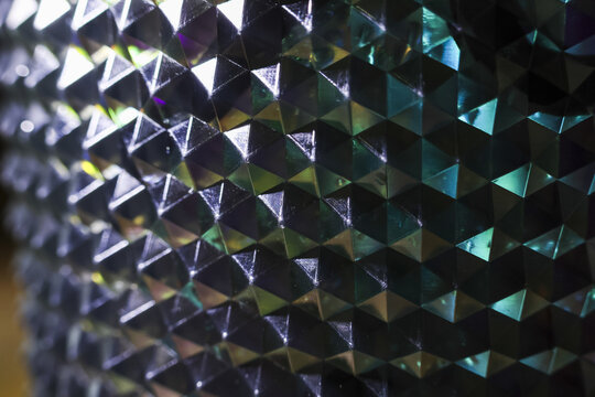 Mesmerizing abstract background of geometric pyramid pattern with holographic texture. futuristic metallic surface reflects iridescent light, creating cool, shiny effect