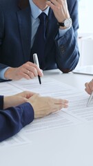 Business people colleagues reviewing contract documents during an office meeting, discussing terms, and preparing for agreement signing, focusing on legal consultation and partnership discussion