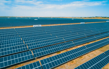 Expansive solar panel arrays under a clear blue sky in a vast renewable energy farm © Evgenii Bakhchev