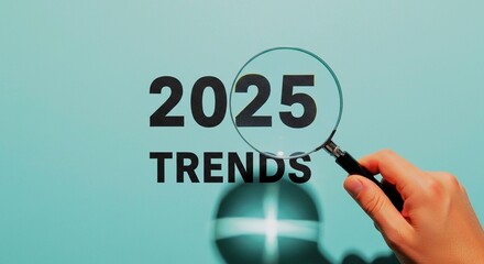 Hand holding a magnifying glass focusing on the text 2025 Trends, symbolizing forecasting and analysis of the future.