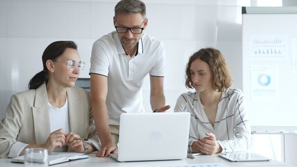 Business team collaborating and analyzing data on a laptop during a productive meeting in a modern office, fostering teamwork and strategic decision making