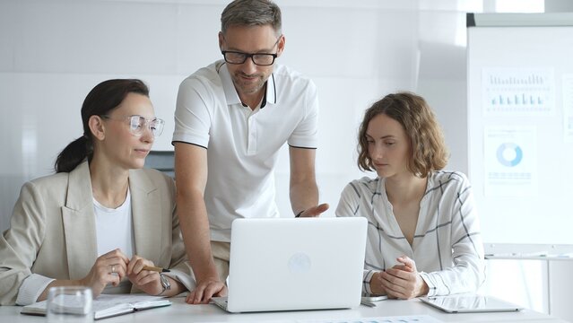 Business team collaborating and analyzing data on a laptop during a productive meeting in a modern office, fostering teamwork and strategic decision making