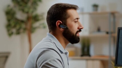 A man wearing a headset and working at his desk. He seems engaged, perhaps in a conversation or a focused task Stock Video - Powered by Adobe