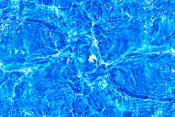 Blue water with ripples on the surface. Defocus blurred transparent blue colored clear calm water surface texture with splashes and bubbles. Water waves with shining pattern texture background.