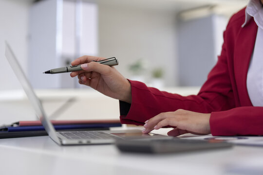 Adult business professional working on laptop computer pointing with pen analyzing data marketing strategy at modern office workspace desk for productivity