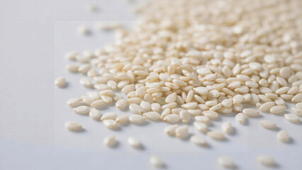 Sesame seeds spilling onto a white surface, creating a textured, organic pattern.
