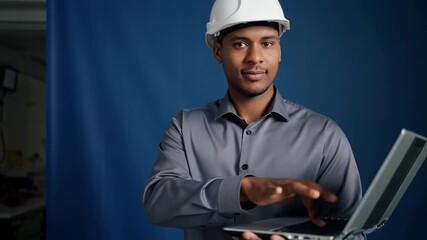 Confident engineer in a helmet, working with a laptop. A professional in a construction field poses and uses a laptop Stock Video - Powered by Adobe
