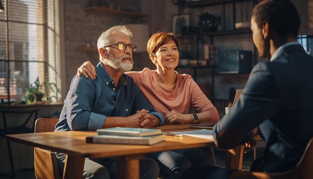 Elderly Couple Smiling and Holding Hands During Meeting with Young Professional in Modern Office
