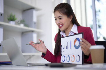 Asian business professional presents financial data online meeting uses laptop computer modern office setting successful women analyzes report performance