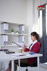 Asian businesswoman reviews business documents modern office desk using laptop for financial planning professional development