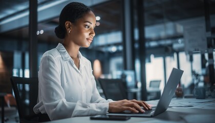 Professional Businesswoman Using Laptop in Modern Office Environment with Natural Light