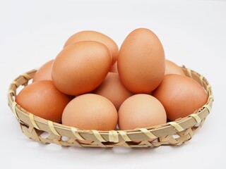 Severil fresh chicken eggs are placed in bamboo basket on a white background.