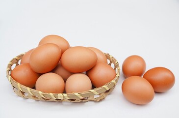 Severil fresh chicken eggs are placed in bamboo basket on a white background.