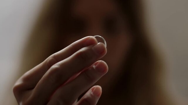 A close-up shot of a person's hand holding a delicate ring, suggesting a moment of reflection or anticipation Stock Video