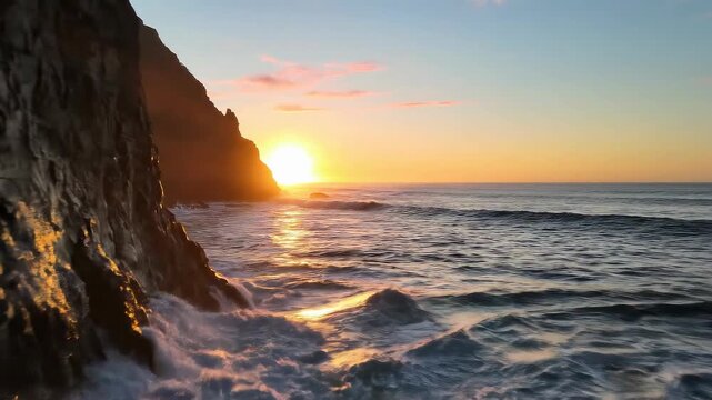 Golden sunset over the ocean with waves crashing against a rocky cliffside.