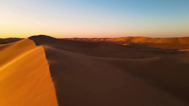 Vast Desert Expanse Dynamic Desert Landscape Footage Wide establishing shot, showcasing endless golden and ochre dunes under a clear, expansive sky.