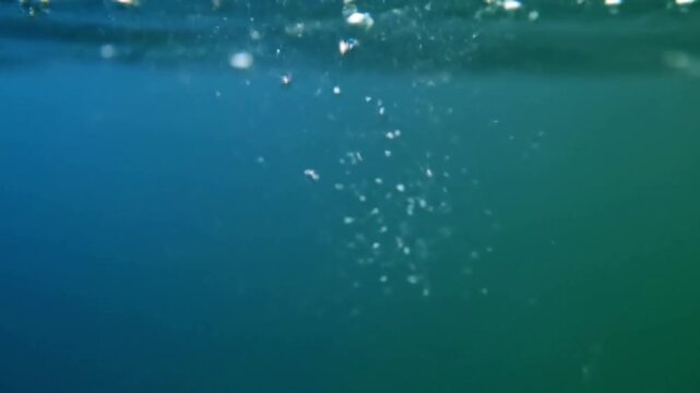 Close up of dew drops on a spiderweb or plant leaf, forming tiny, perfect spheres that shimmer with reflected light from a natural, blurred background.