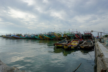 a row of traditional fishing boats at a port in Indonesia with calm seas and cloudy skies 2