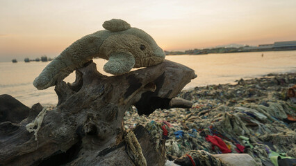 A dolphin doll stuck on a piece of wood along with the rubbish that washed up on the beach near the harbor and the fishing village settlement, photographed in the morning with calm seas 7