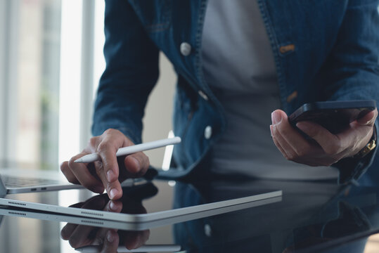 Close up of young asian business woman in casual wear using digital tablet with laptop computer on office table. Website designer, entrepreneur working on digital tablet technology