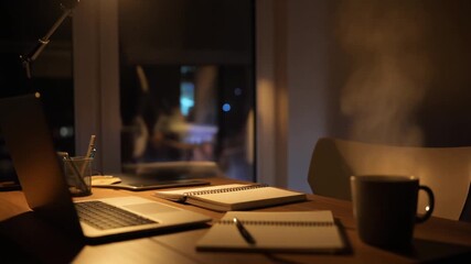 Cozy home office setup with laptop, notebooks, and coffee mug for productive work at night